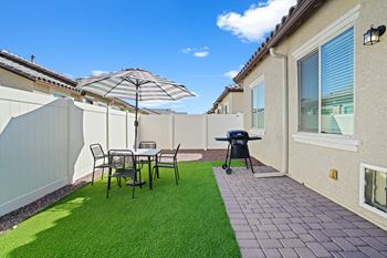 A backyard with a table and chairs and a grill
